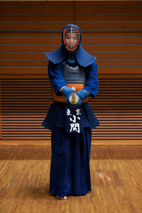 Kendoka in chūdan-no-kamae wearing full bogu, facing forward in a dojo