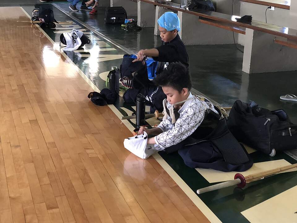 Kendoka folding a tenugui headcloth before putting on men